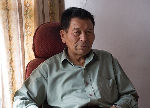 Chewang Norphel seated indoors, smiling slightly