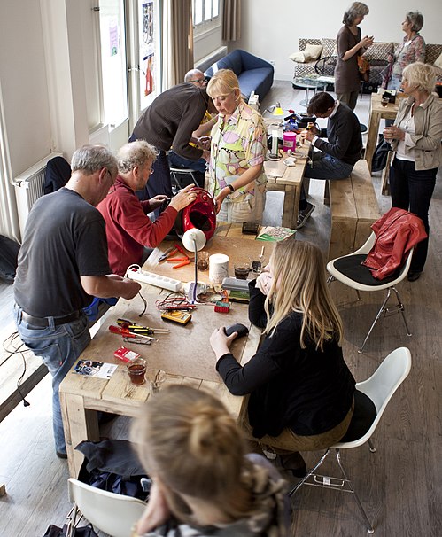 Volunteers and visitors around tables, repairing household items together at a Repair Café