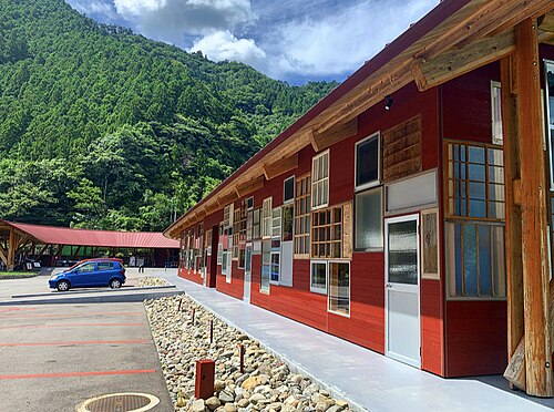 The long, low timber Zero Waste Center building in Kamikatsu, with wooded mountains behind