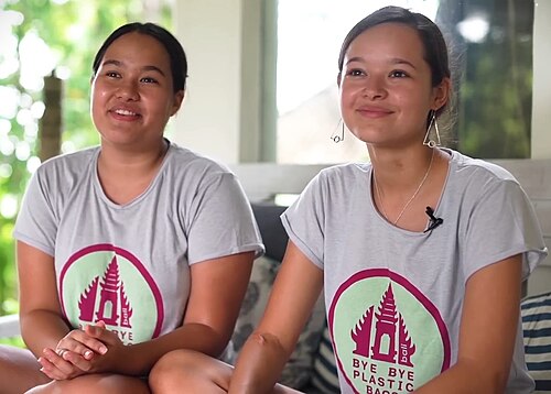 Sisters Isabel and Melati Wijsen sitting side by side in Bye Bye Plastic Bags T-shirts